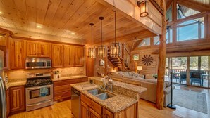 A spacious kitchen with wooden cabinets, stainless steel appliances, and a granite countertop. - Heaven on the Lake - Lakefront | Hot Tub | Fire Pit | Game Room (Blue Ridge)