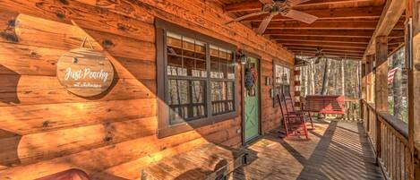 A wooden cabin with a porch, a sign reading "Just Peachy," and a green door.