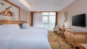 A hotel room with two beds, a desk, a chair, a television, and a large window with curtains. - Vienna International Hotel (Maoming)