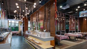 A restaurant with a long counter, hanging lights, and a display of dishes. - Vienna International Hotel (Maoming)