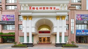 A hotel entrance with a grand archway, a sign indicating CCTV surveillance, and a Vienna Cinema sign on the right. - Vienna International Hotel (Maoming)