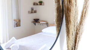 Quarto com cama, mesa de cabeceira, espelho e planta em vaso.