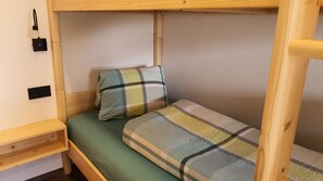 Kerrossänky, jossa on vihreä patja ja ruudullinen vuodevaatteisto.