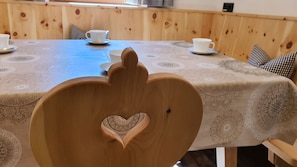 Een houten tafel met een hartvormige uitsparing in de rugleuning van een stoel.