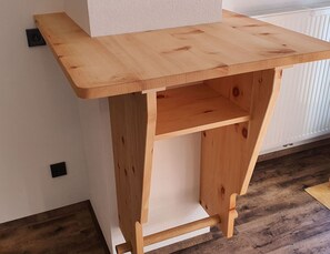 Ein Holztisch mit Ablage, platziert an einer Wand mit Heizkörper.
