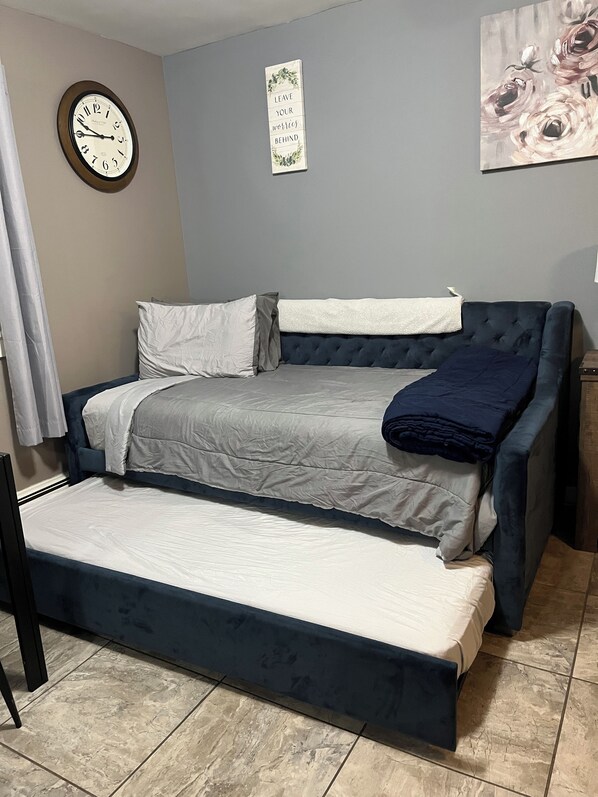 Um quarto com uma cama, uma mesa de cabeceira, um relógio e uma obra de arte na parede.