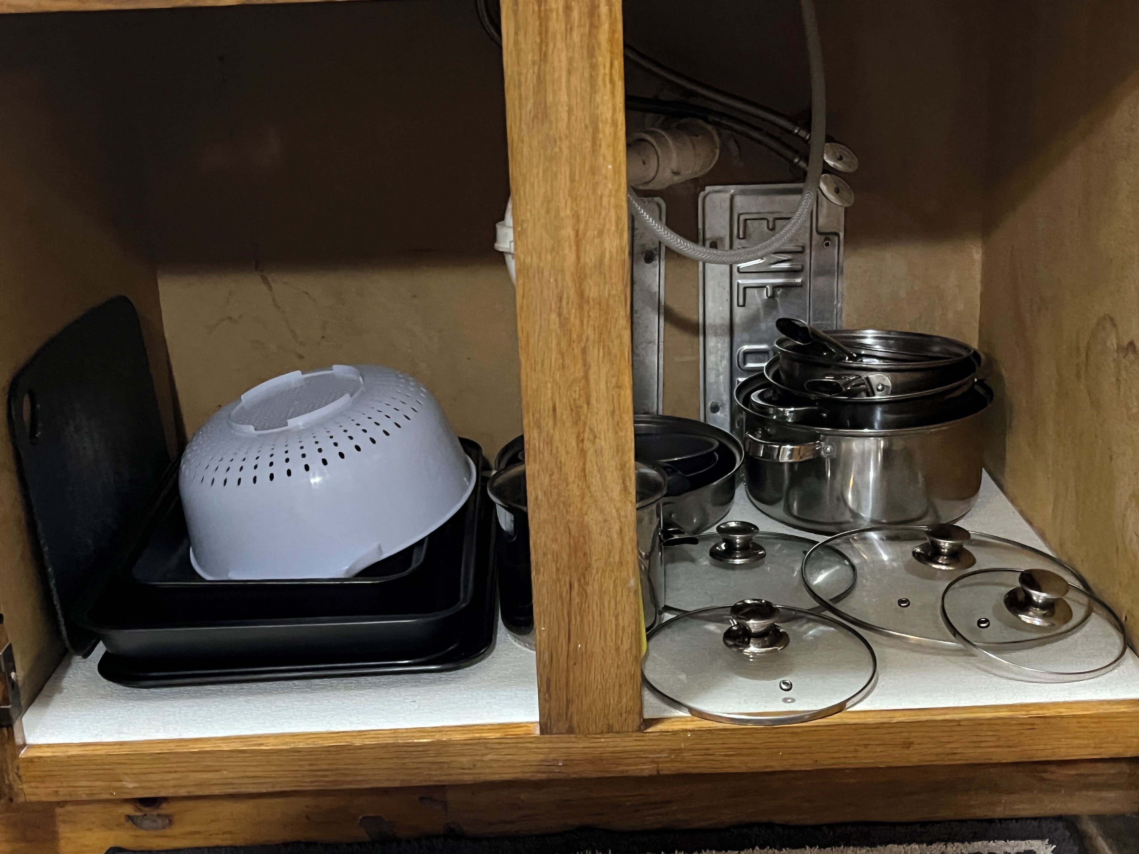 A kitchen area with a colander, pots, and a stove.