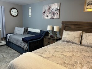 A bedroom with two beds, a clock, a motivational quote, and a floral painting. - Just Like Being At Home- Newly Renovated Unit (North Troy)
