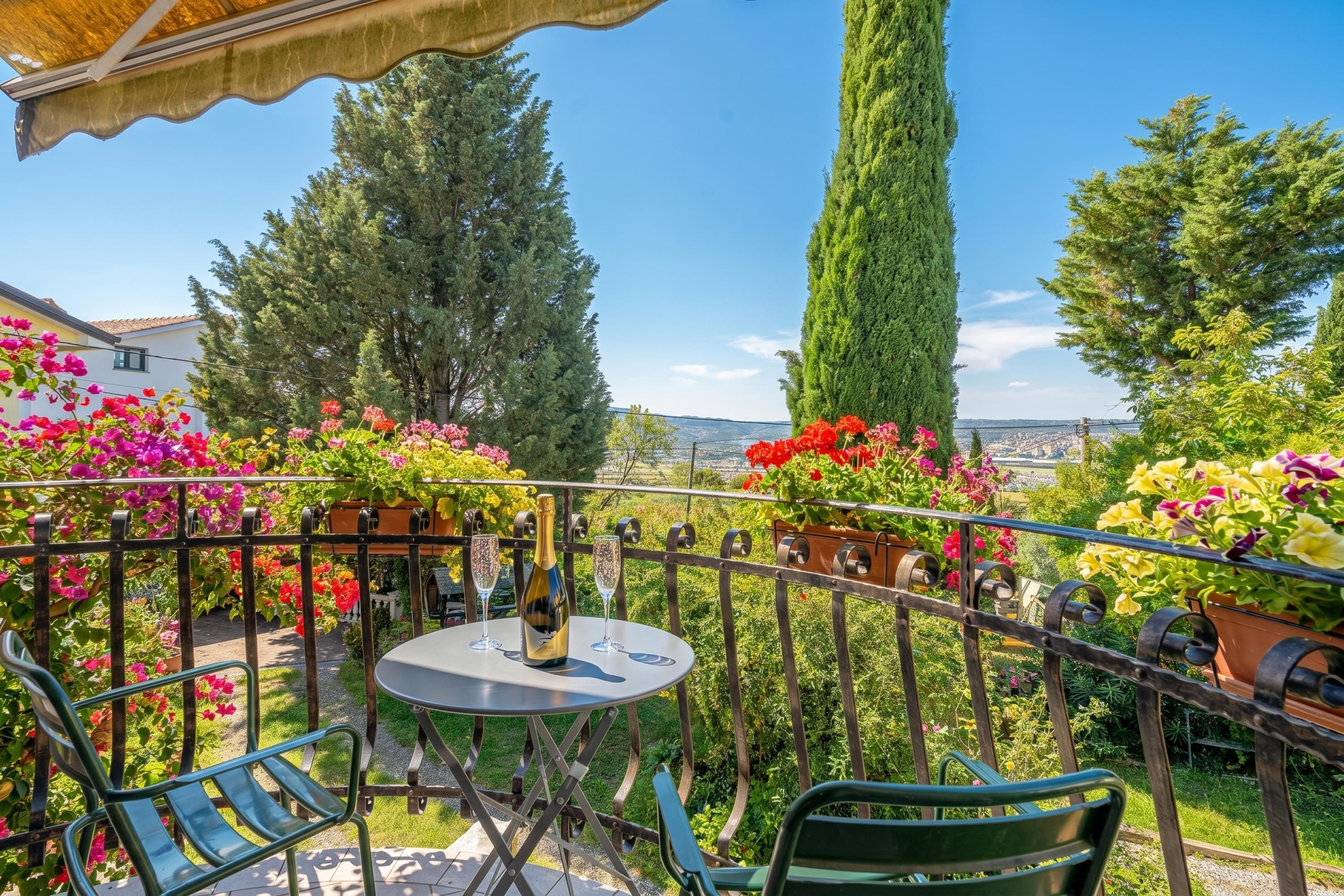 A balcony with a table, chairs, and a bottle of champagne.