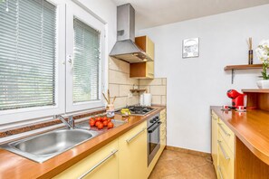 A kitchen with a stainless steel sink, wooden countertop, yellow cabinets, a gas stove, and a red electric kettle. - House In The Vineyards Ankaran (Ankaran)
