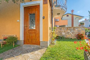 A house with a wooden door, stone steps, and a small garden with flowers. - House In The Vineyards Ankaran (Ankaran)