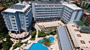 Un hotel amb diverses plantes, una piscina al terrat i un pati amb jardí.