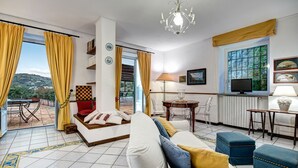 A modern living room with a sofa, ottomans, a dining table, and a TV. - Country Lemonvilla (Massa Lubrense)