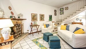 A living room with a white sofa, blue ottomans, a fireplace, and a staircase. - Country Lemonvilla (Massa Lubrense)