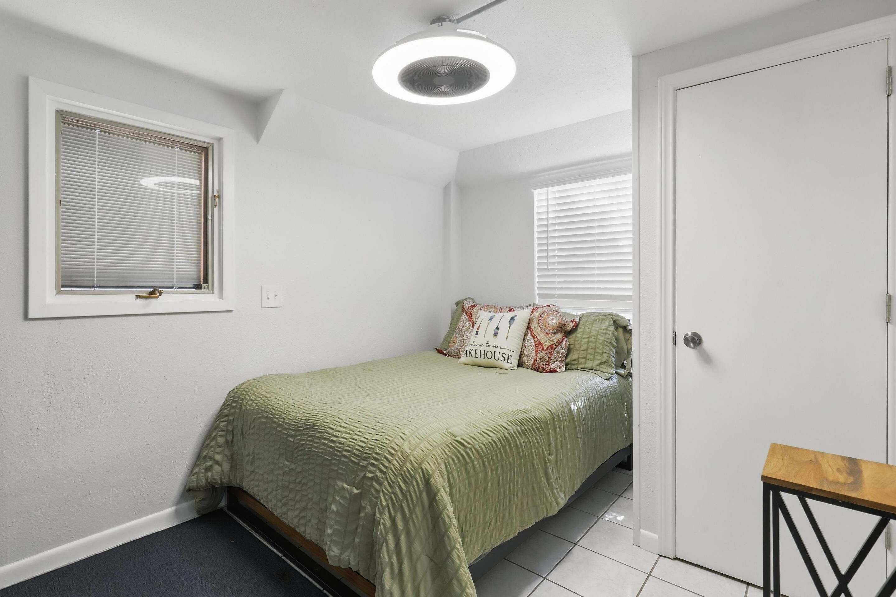 A small, clean bedroom with a single bed, a bedside table, and a door.