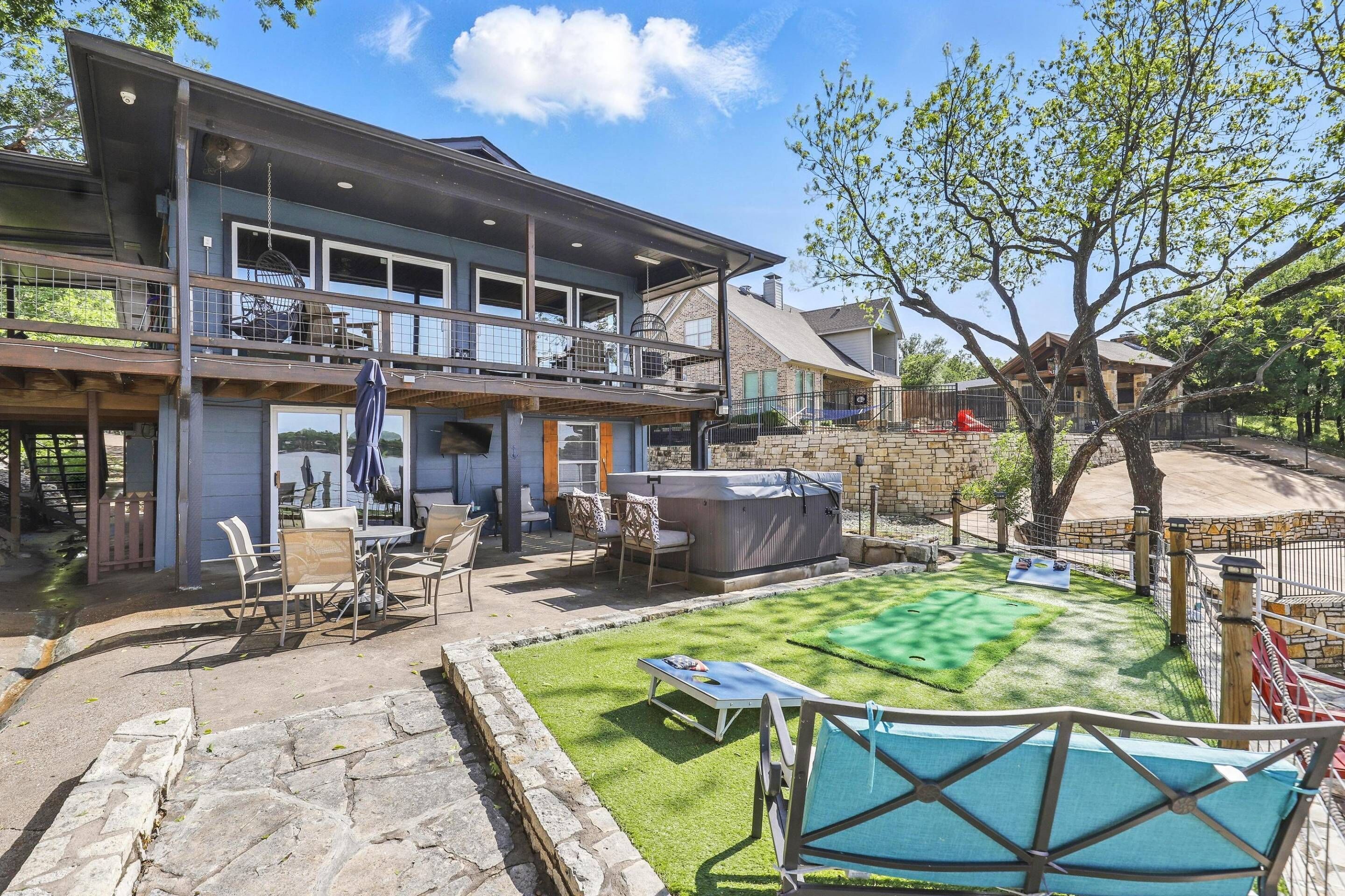 A two-story house with a patio area, outdoor seating, and a hot tub.