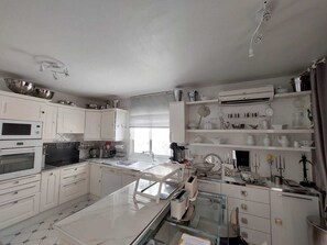 A modern kitchen with white cabinets, a microwave, oven, and a glass dining table.