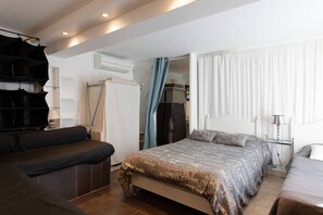 A bedroom with a bed, a sofa, and a desk.