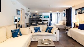 Ein modernes Wohnzimmer mit einer Sofagarnitur, einem Essbereich und einer Küche im Hintergrund.