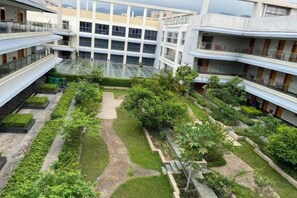 A multi-story building with a courtyard featuring pathways, greenery, and a glass atrium. - Perthden (Hanging) Gardens Hotel (Shenzhen)