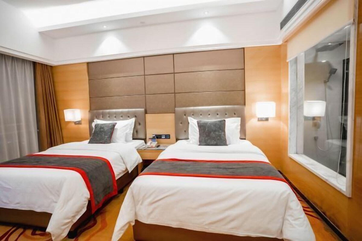 A hotel room with two beds, a large window, and a modern design.
