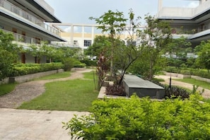A courtyard with a central pathway, surrounded by greenery and modern buildings. - Perthden (Hanging) Gardens Hotel (Shenzhen)