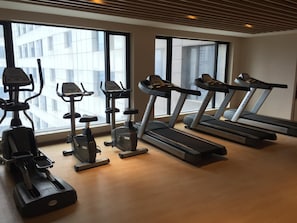 A gym with various exercise machines, large windows, and a wooden floor. - Zhujiang New Town Hampton Hilton (Guangzhou)