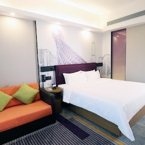 A hotel room with a bed, a sofa, a nightstand, and a wall with a cityscape mural. - Zhujiang New Town Hampton Hilton (Guangzhou)
