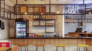 Un espace bar avec des tabourets, des étagères remplies de bouteilles et un réfrigérateur.