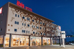 A hotel with a checkered facade, a prominent 'ibis HOTEL' sign, and a well-lit entrance. - ibis Caucaia Porto do Pecém (Caucaia)