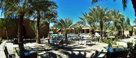 Un resort con terraza al aire libre, piscina y palmeras.