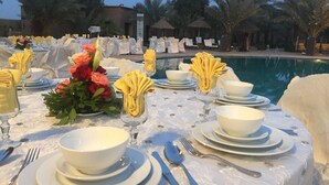A table set for a formal dinner with white tablecloths, plates, bowls, and silverware. - Palms Hotel Club (Aarab Sebbah Ziz)