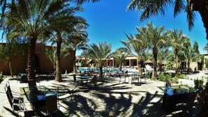 A resort with outdoor seating, a pool, and palm trees. - Palms Hotel Club (Aarab Sebbah Ziz)