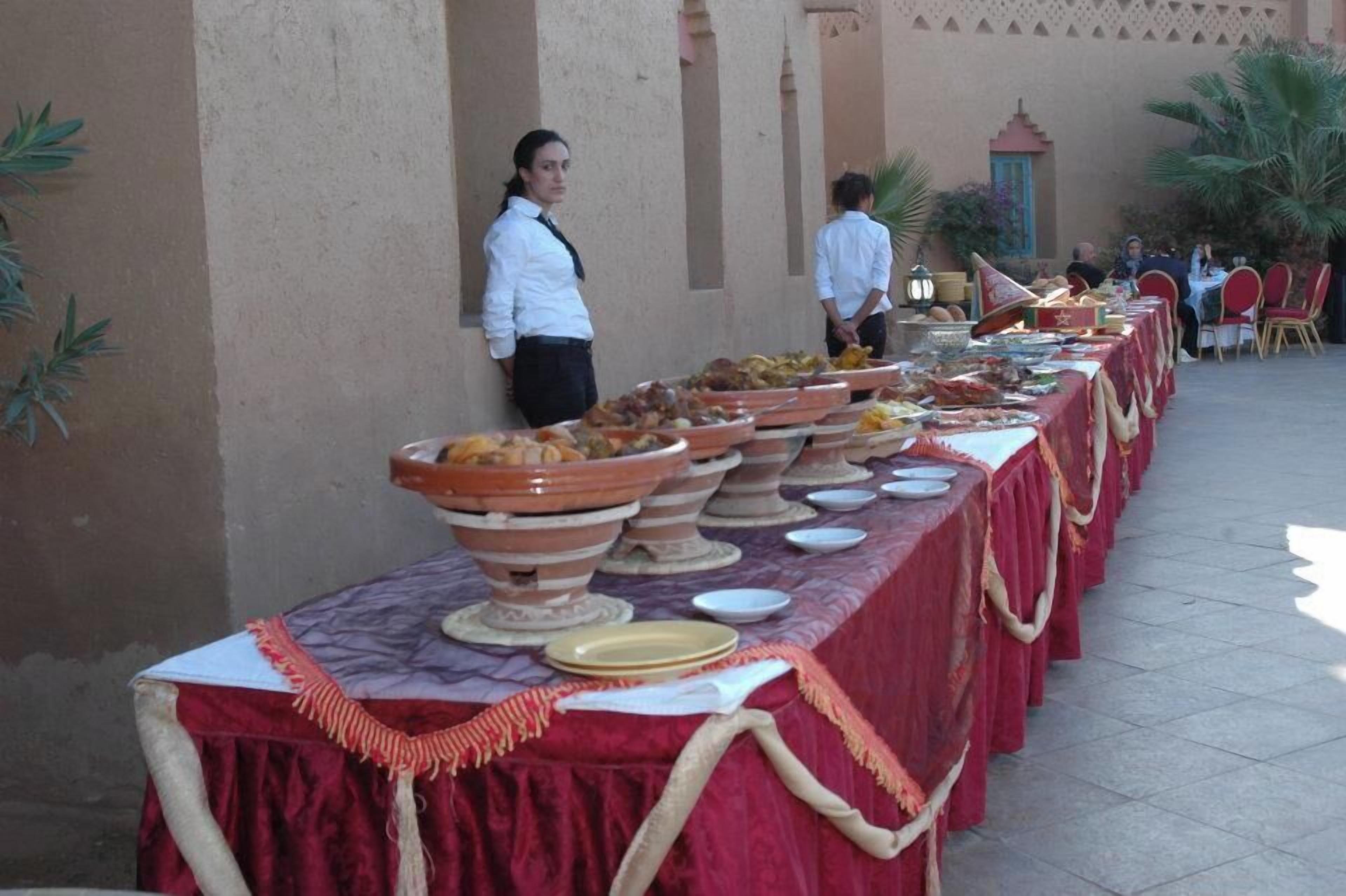 A buffet setup with multiple serving dishes and a long table covered with a red cloth.