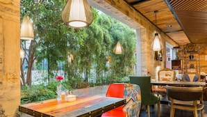 An indoor dining area with a wooden table and chairs, surrounded by greenery and hanging lights. - Fudi Hotel (Shanghai)
