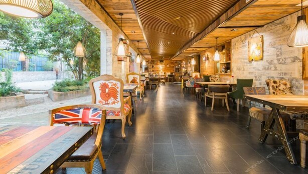 An indoor dining area with wooden ceiling beams, tables with chairs, and hanging pendant lights. - Fudi Hotel (Shanghai)
