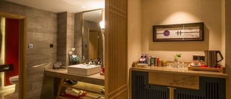 A modern bathroom with a large mirror, a sink, and a vanity with toiletries.