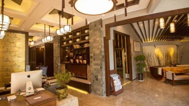 A lobby with a reception desk, a bookshelf, and a seating area with a table and chairs. - Yongkang Huihe Hotel (Yongkang)