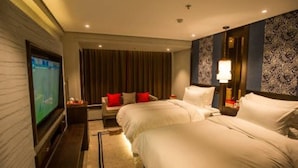 A hotel room with two beds, a TV, a desk, and a patterned wall. - Yongkang Huihe Hotel (Yongkang)