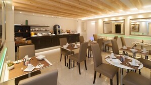 Un espace de repas moderne avec des poutres en bois au plafond, une cuisine centrale et plusieurs tables à manger accompagnées de chaises.