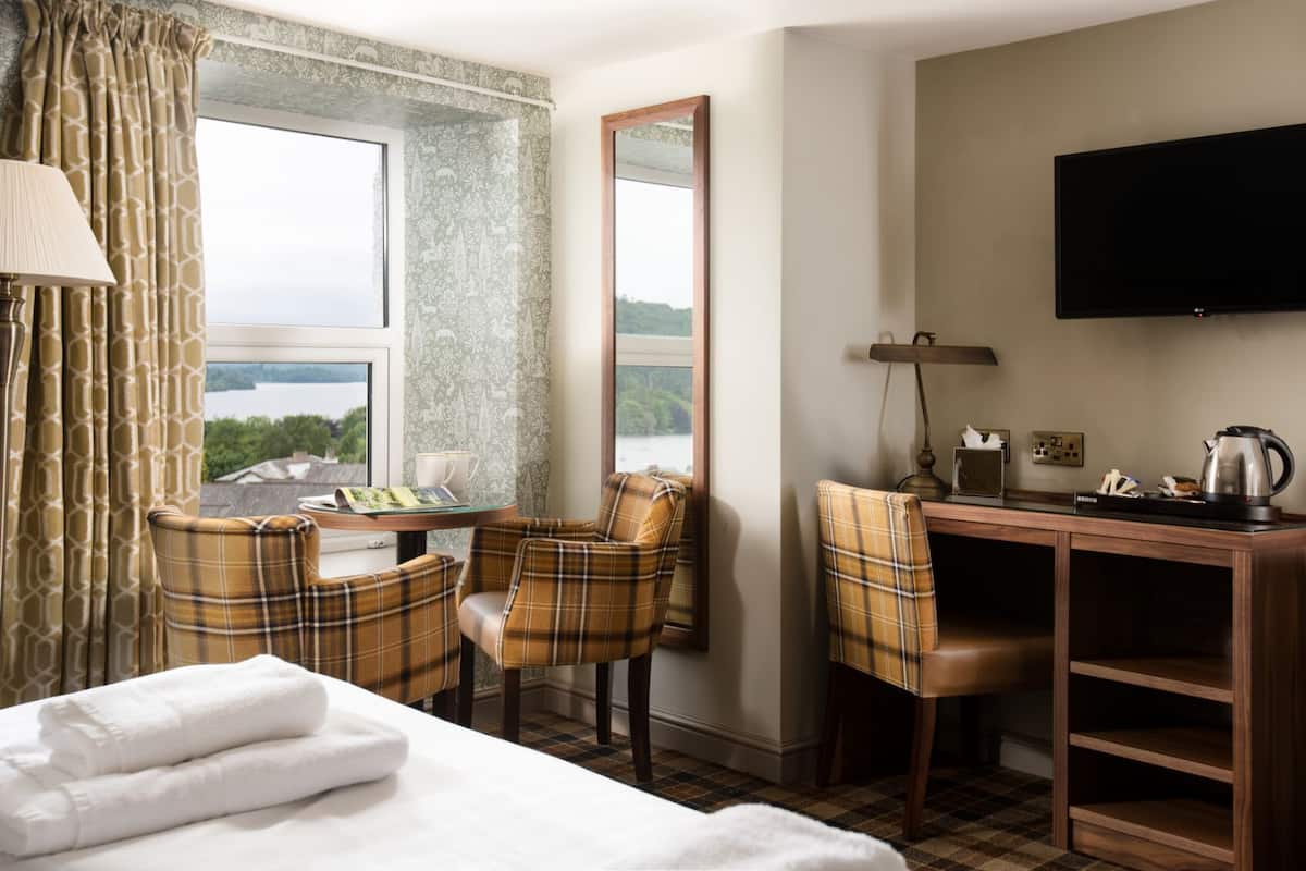 A hotel room with a bed, a desk with a chair, a television, and a view of the outdoors.