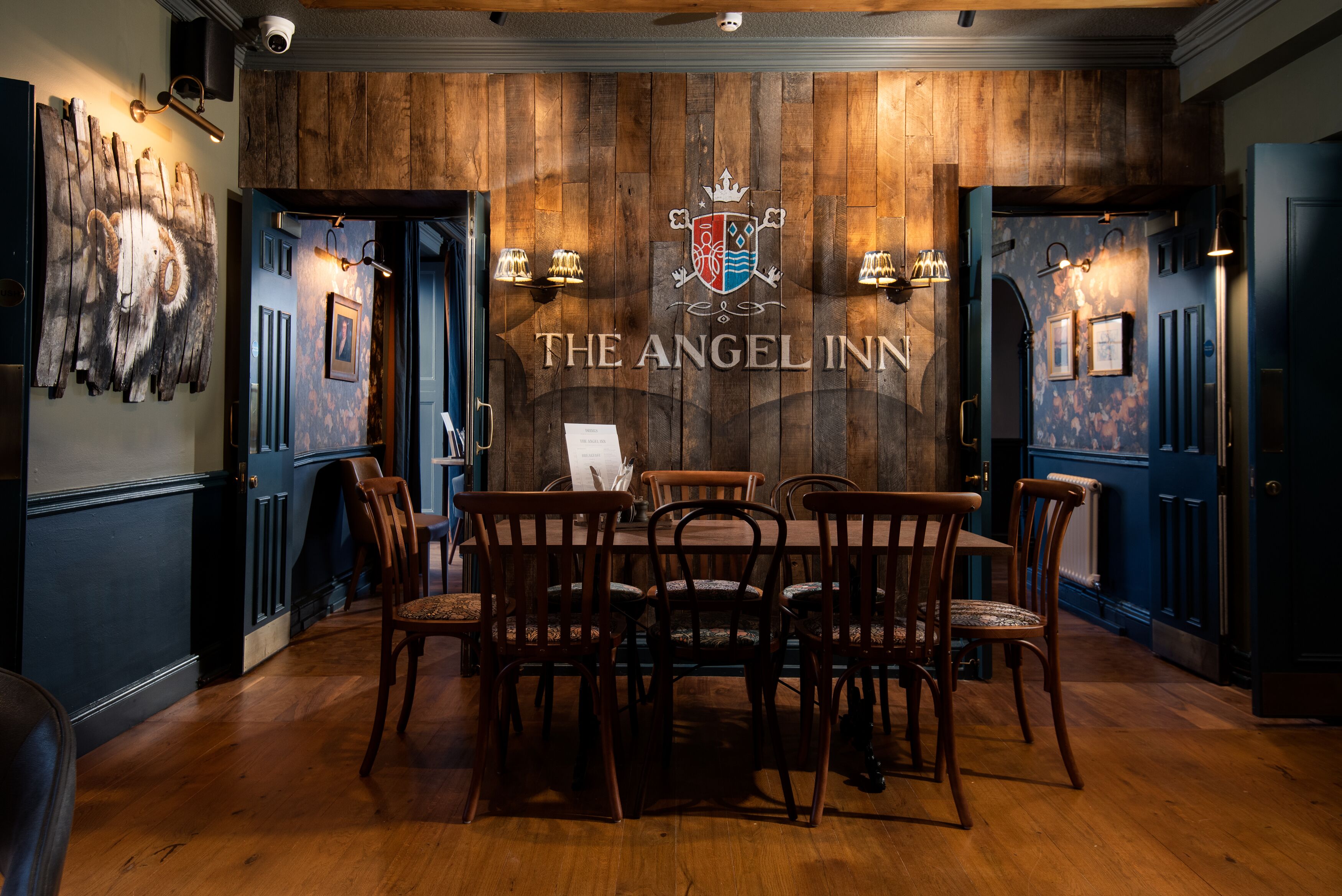 A dining area with wooden walls, a table, and chairs at The Angel Inn.