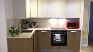 Una cocina moderna con armarios de madera, microondas, tostadora y pileta.