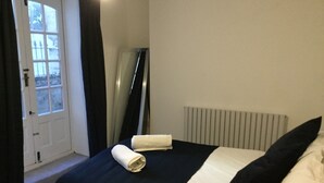 Una cama bien tendida con edredón blanco y negro, una toalla enrollada y una almohada negra.