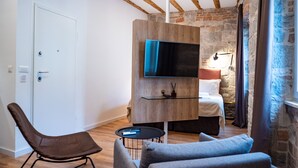 A modern living room with a sofa, a chair, a TV mounted on a wooden wall, and a stone fireplace. - Emarconi history&luxury in Split center (Split)