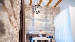 A dining area with a stone wall, wooden beams, and a table with chairs. - Emarconi history&luxury in Split center (Split)