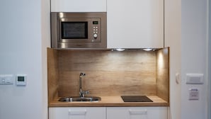 A compact kitchen with a built-in microwave, a sink, and wooden cabinetry. - Emarconi history&luxury in Split center (Split)