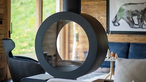 A modern living room with a circular black object, a wooden wall, a framed animal picture, and a blue sofa. - Chalet Anthocyane, 14 pers, piscine chauffée, sauna, pistes à 100 m (LA CLUSAZ)