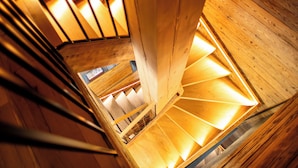 A wooden spiral staircase with a metal railing, leading to a lower level. - Chalet Anthocyane, 14 pers, piscine chauffée, sauna, pistes à 100 m (LA CLUSAZ)