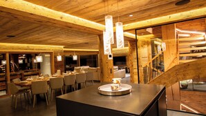 A wooden interior with a dining area, a staircase, and a bar area. - Chalet Anthocyane, 14 pers, piscine chauffée, sauna, pistes à 100 m (LA CLUSAZ)